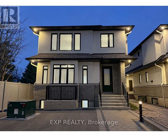 A modern house with a dark front porch and a green dumpster in front.