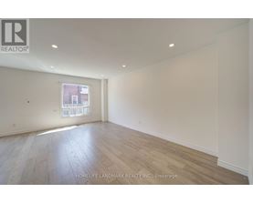 A room with wooden flooring and a window showing a view of a building outside.