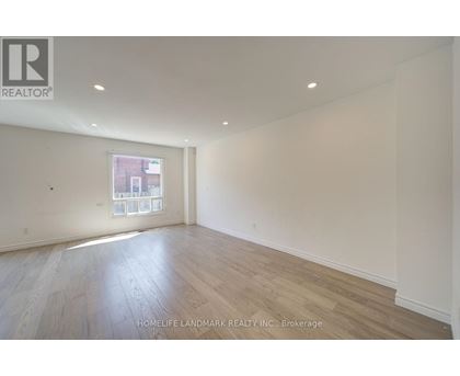A room with wooden flooring and a window showing a view of a building outside.