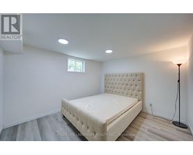 A bedroom with a bed, lamp, and a window.