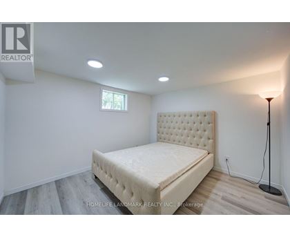 A bedroom with a bed, lamp, and a window.
