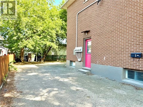 A red door is on the side of a brick building.