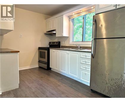 A kitchen with a refrigerator, oven, and sink.