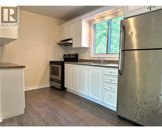 A kitchen with a refrigerator, oven, and sink.