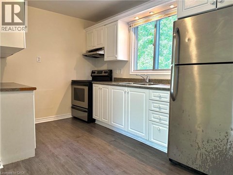 A kitchen with a refrigerator, oven, and sink.