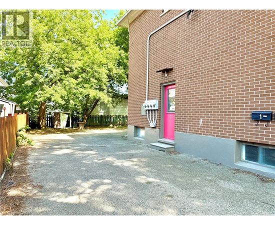 A red door is on the side of a brick building.