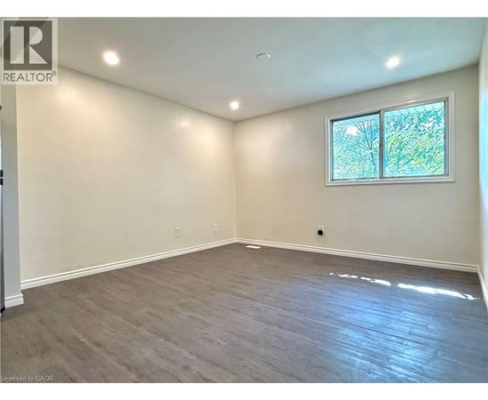 A room with a window and a wooden floor.