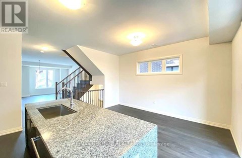 A kitchen with a granite countertop and a staircase in the background.