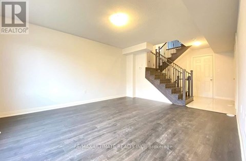 A spacious room with a staircase leading to another floor.