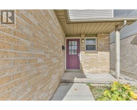 A brick house with a purple door and a small window.