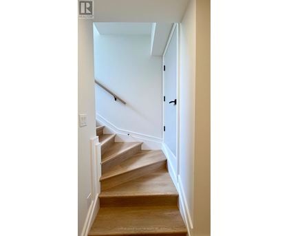 A staircase with a wooden handrail and steps leading up to a door.