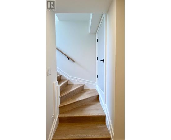 A staircase with a wooden handrail and steps leading up to a door.
