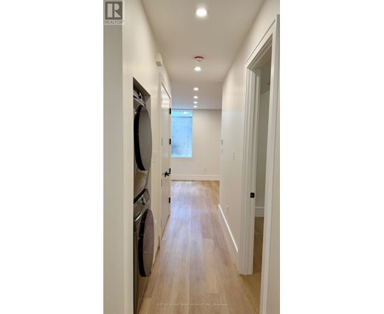 A long hallway with a washer and dryer on the left.