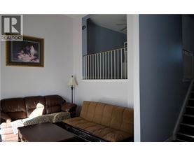 A living room with a brown couch and a painting on the wall.
