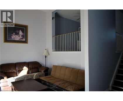 A living room with a brown couch and a painting on the wall.