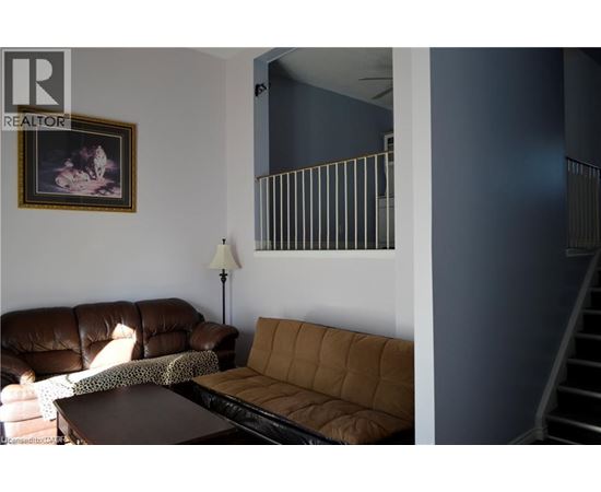 A living room with a brown couch and a painting on the wall.