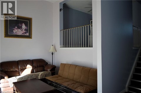 A living room with a brown couch and a painting on the wall.