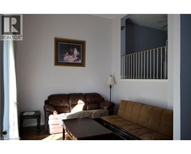 A living room with a brown couch and a painting on the wall.