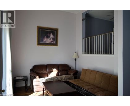 A living room with a brown couch and a painting on the wall.
