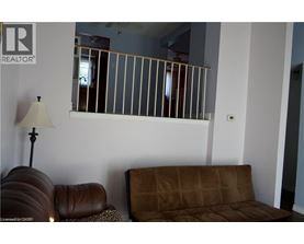 A brown couch sits in front of a wall with a mirror and lamp.