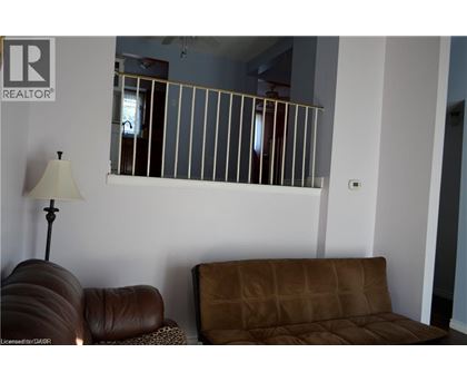 A brown couch sits in front of a wall with a mirror and lamp.
