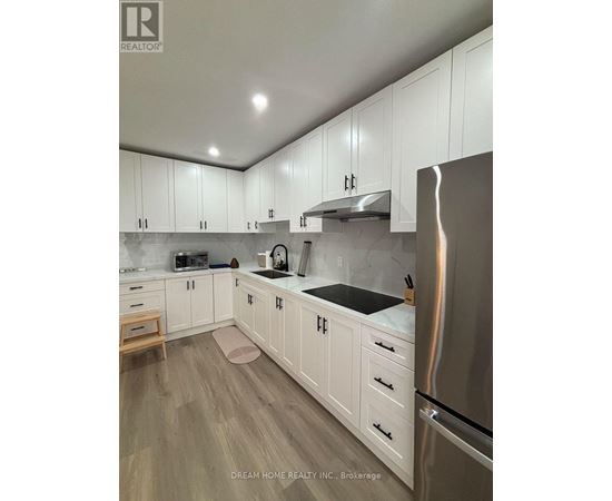 A kitchen with white cabinets and a stainless steel refrigerator.