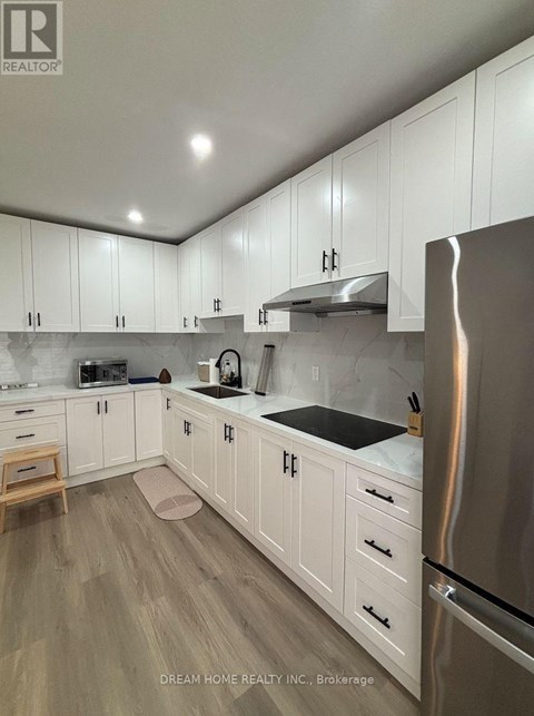 A kitchen with white cabinets and a stainless steel refrigerator.