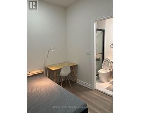 A bedroom with a bed, desk, and chair.