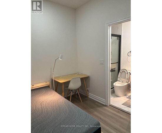 A bedroom with a bed, desk, and chair.