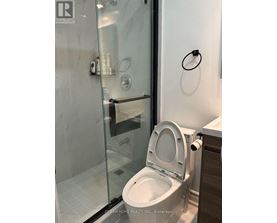 A white toilet in a modern bathroom with a glass shower door.