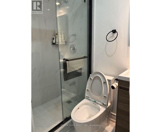 A white toilet in a modern bathroom with a glass shower door.