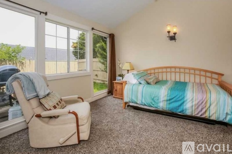A bedroom with a bed, chair, and window.