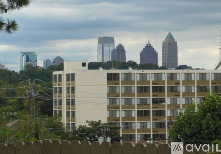 A tall building with many windows is in the foreground with a city skyline in the background.