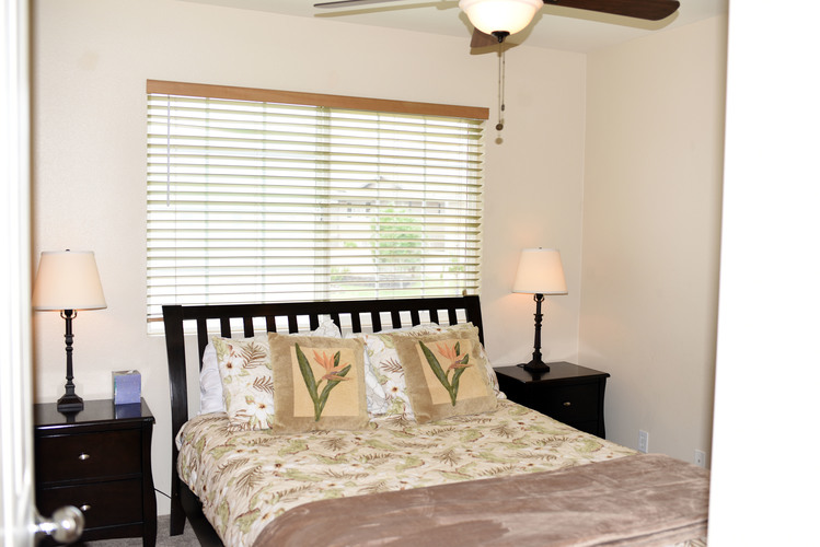 A bedroom with a bed, two lamps, and a ceiling fan.
