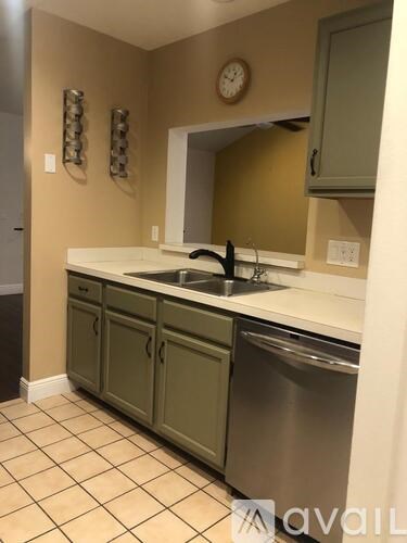 A kitchen with a stainless steel dishwasher and green cabinets.