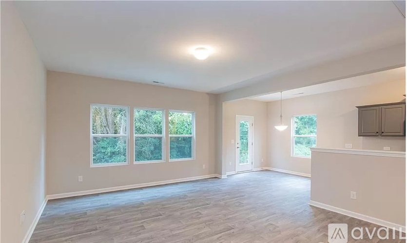 A spacious room with a large window and a door leading to another room.