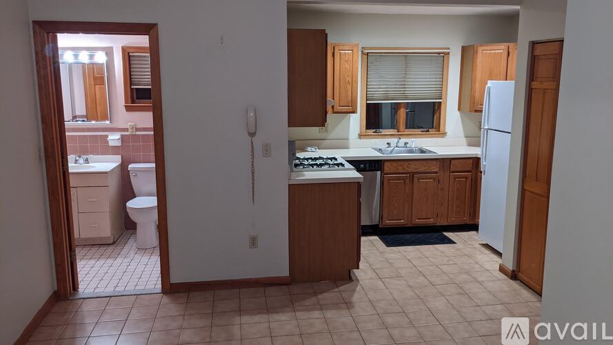 A kitchen with a refrigerator, sink, and cabinets.
