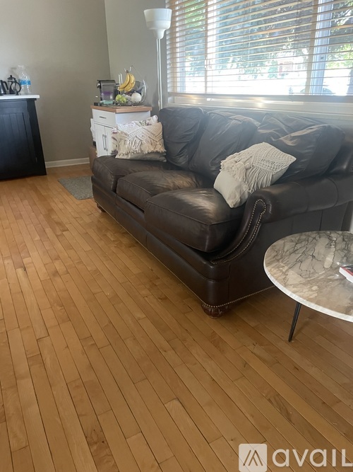 A living room with a brown couch and a round marble table.