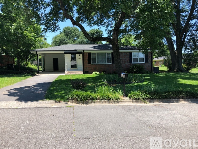 A house with a driveway and greenery in front.