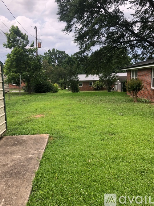 A backyard with a concrete slab and a house in the background.