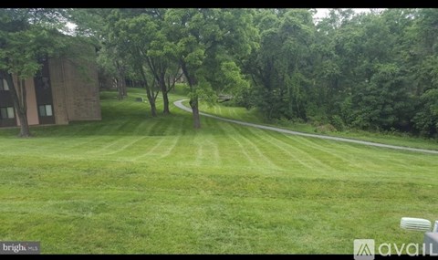 A grassy field with trees and a building in the background.