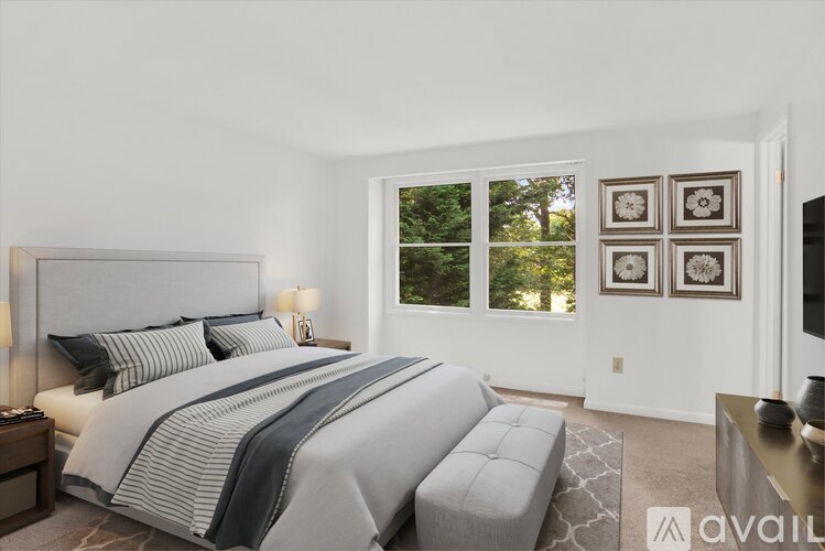A bedroom with a large bed and a window with a view of trees.