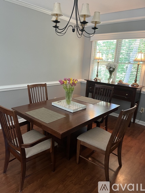 A dining room with a table set for two and a chandelier.