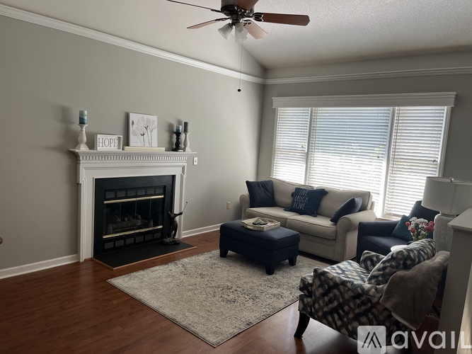 A living room with a fireplace, couches, and a rug.