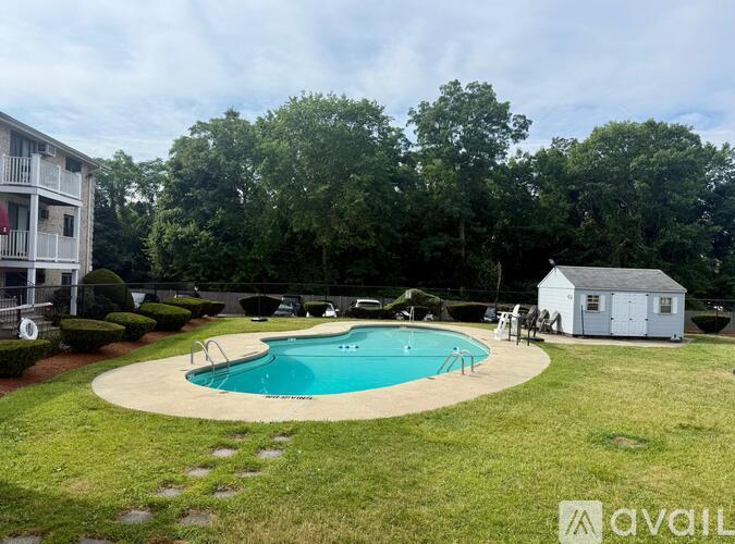 A swimming pool surrounded by a grassy area and trees.