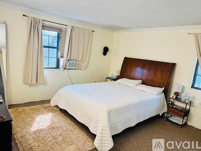 A bedroom with a large bed and a window with curtains.