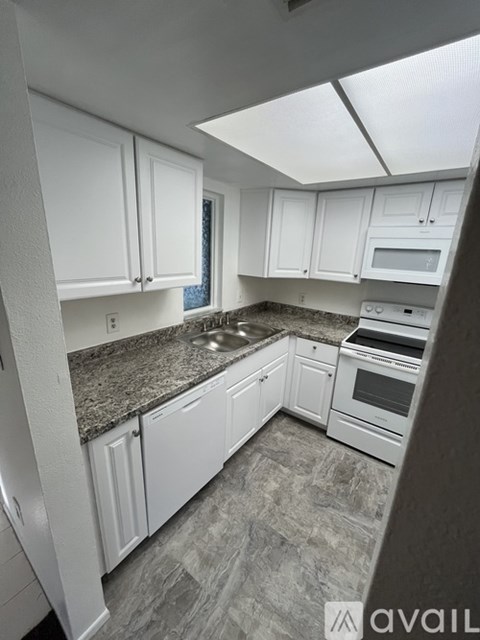 A kitchen with white cabinets and granite countertops.
