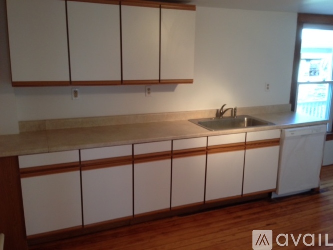 A kitchen with white cabinets and a wooden floor.