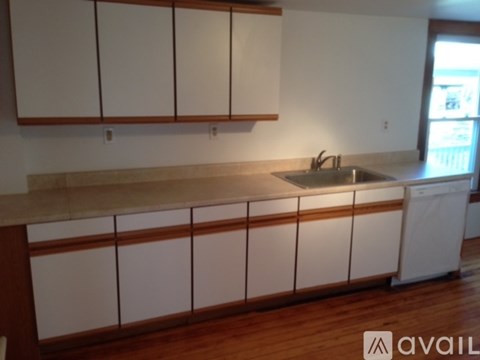 A kitchen with white cabinets and a wooden floor.