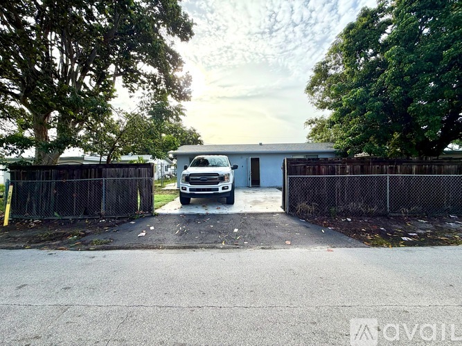 A car is parked in front of a white building with a black fence.